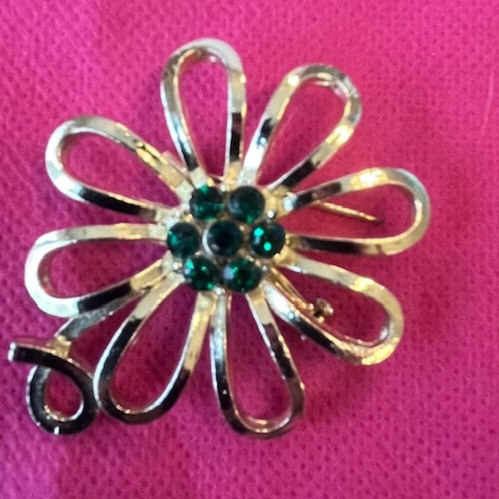 A gold-tone floral brooch with green glass or paste stones